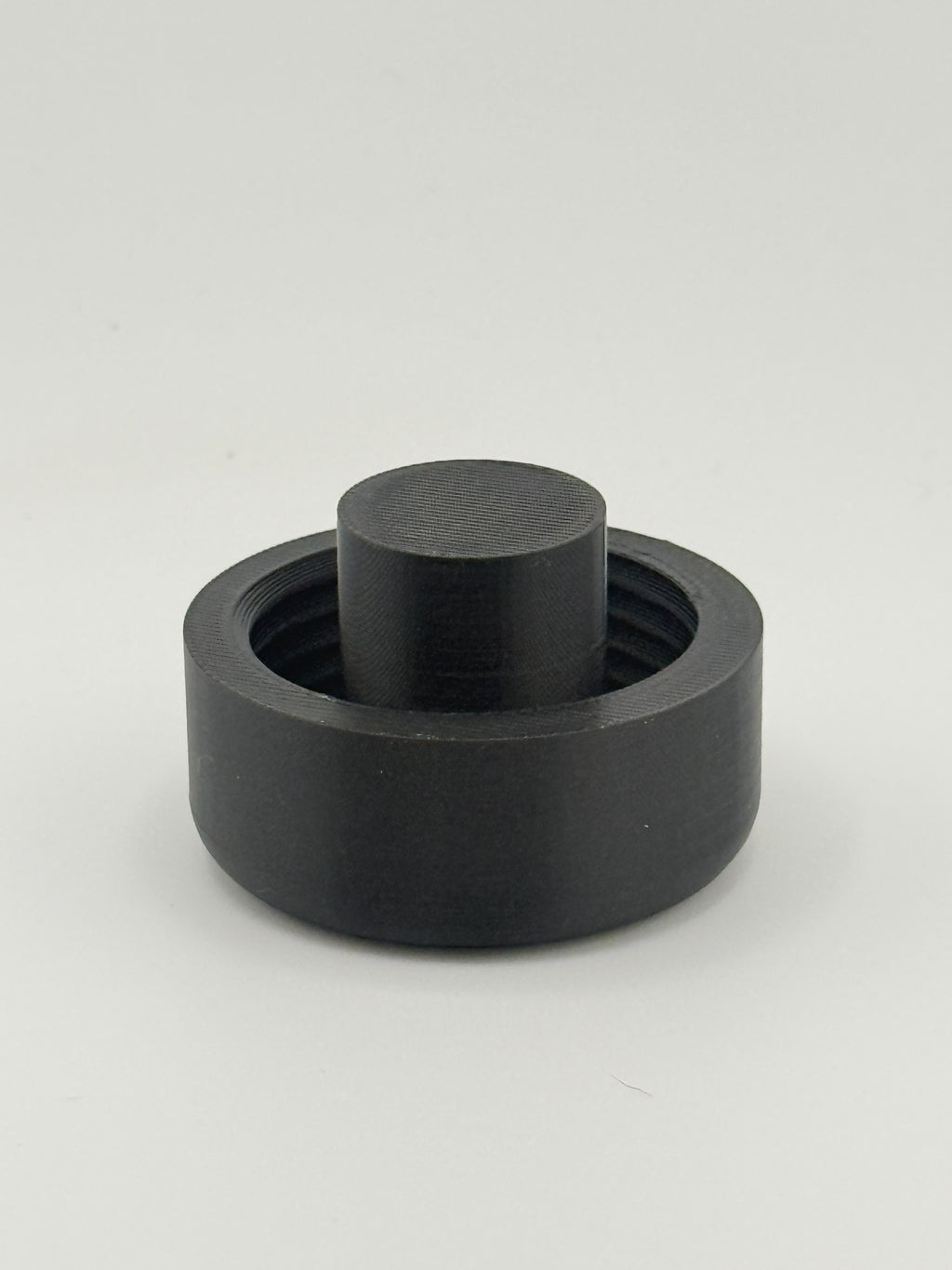 Single black TrackMount extended cap with the tall protruding stop rib used for securing to thinner white canes