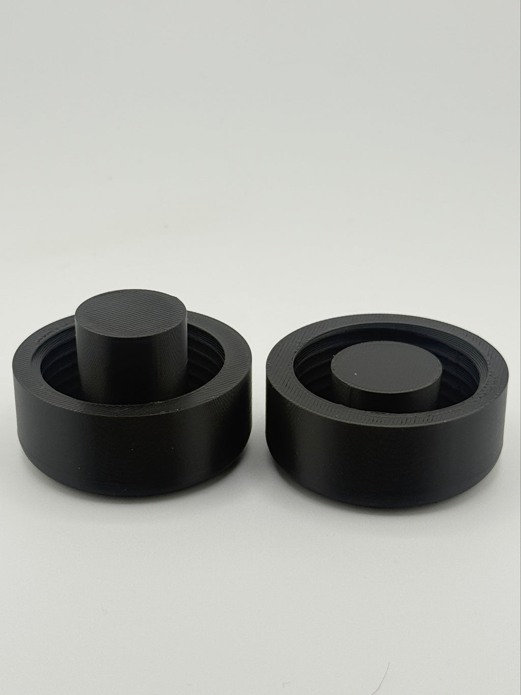 Two black TrackMount clamping caps: one for standard canes and one for thinner white canes