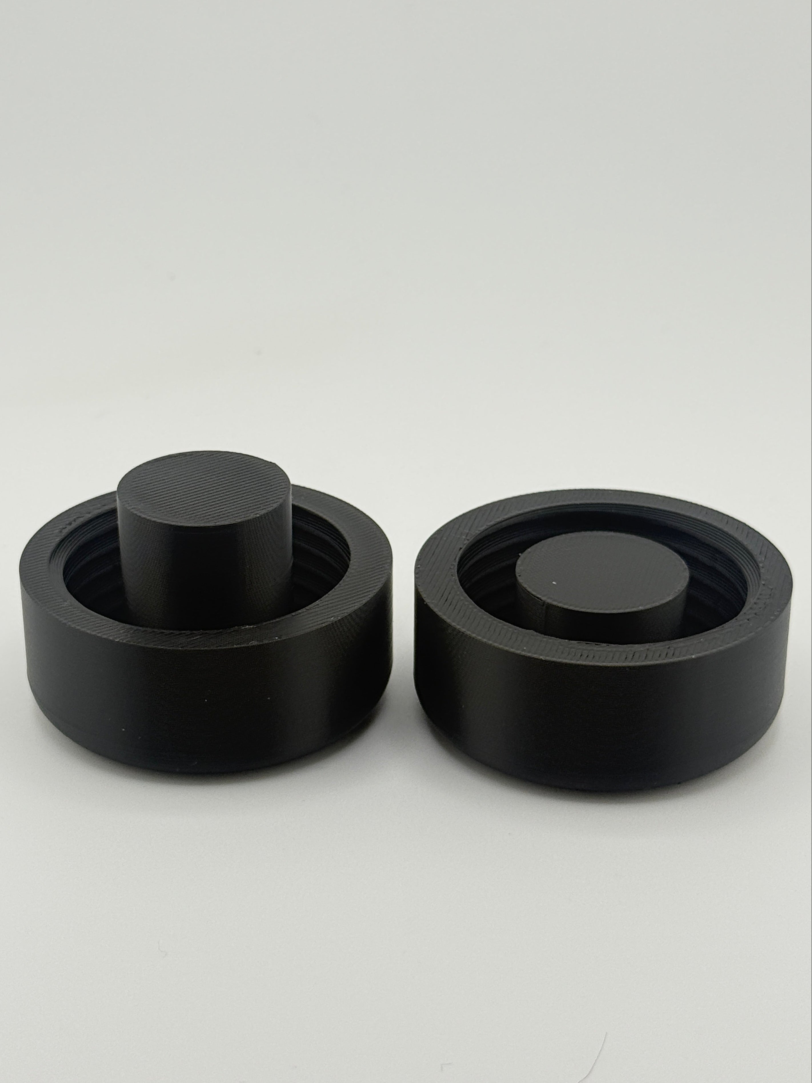 Two black TrackMount clamping caps: one for standard canes and one for thinner white canes