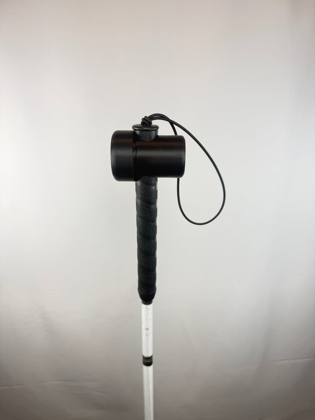 Black TrackMount with the main cap mounted on a thin white cane handle right below the wrist strap