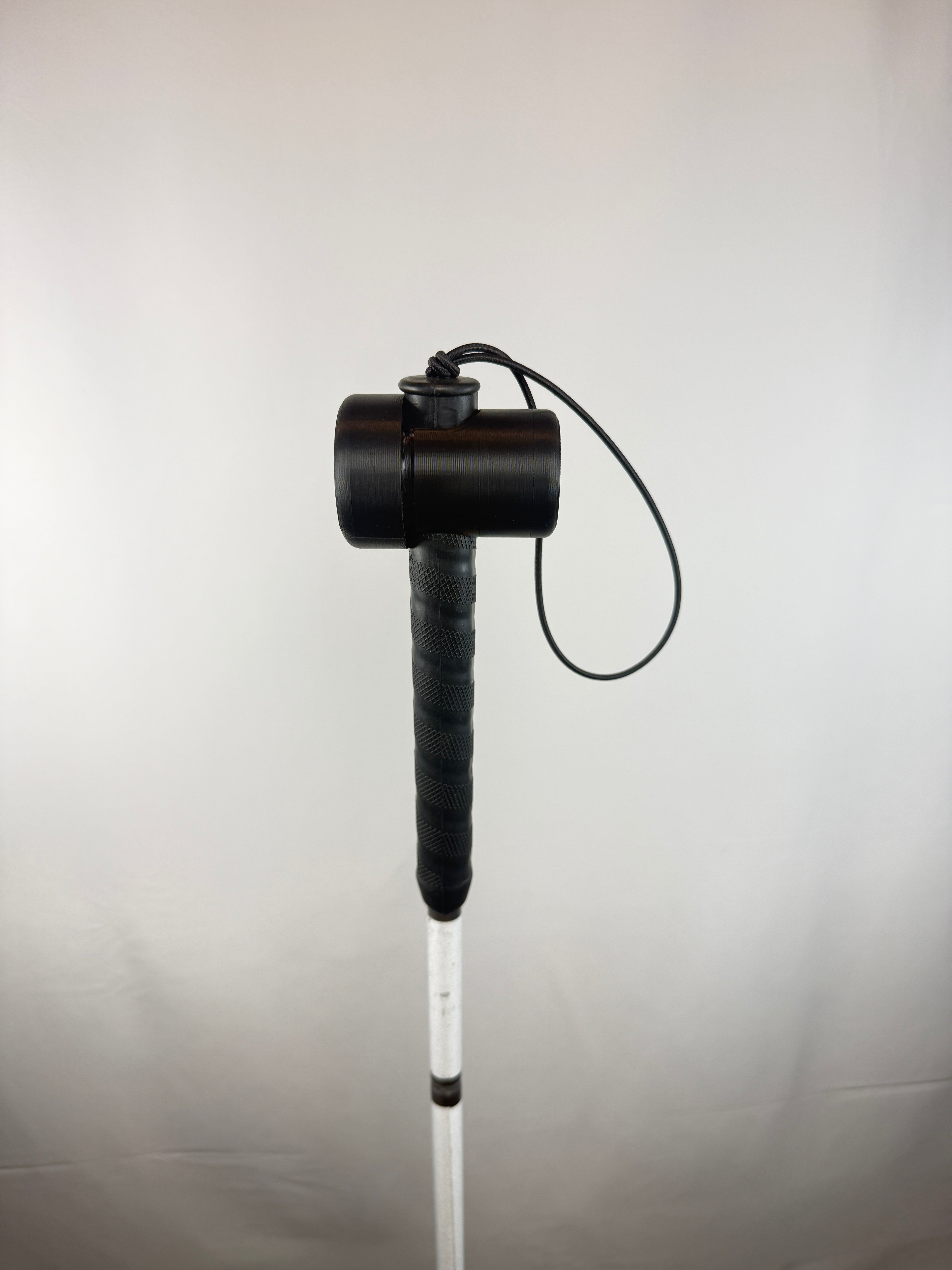 Black TrackMount with the main cap mounted on a thin white cane handle right below the wrist strap