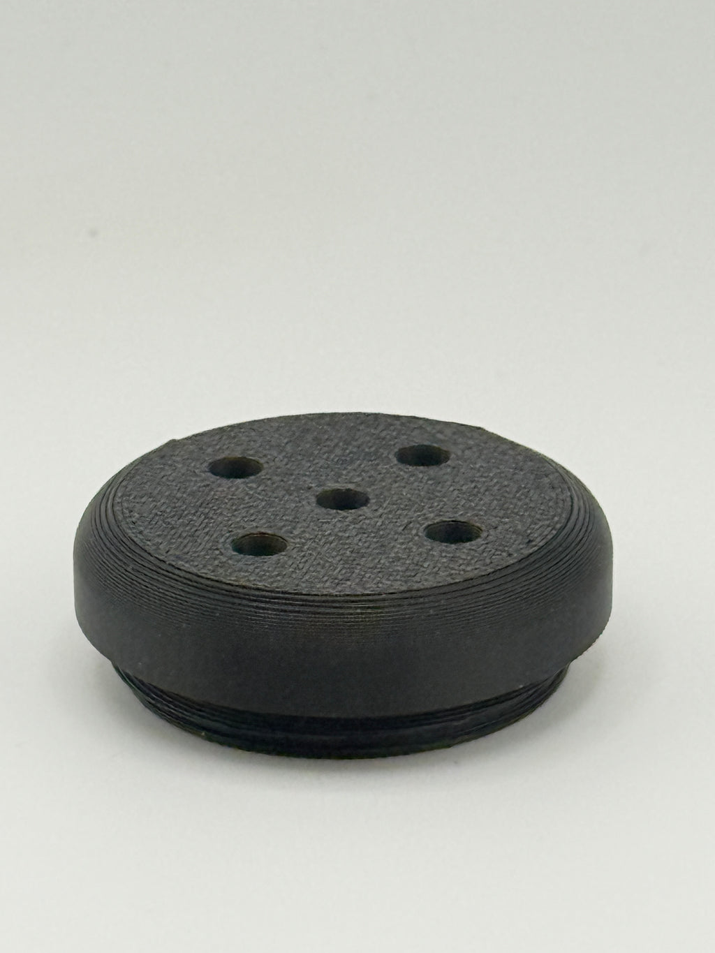 Black perforated TrackMount tracker cap with five holes that let the tracker chime sound through