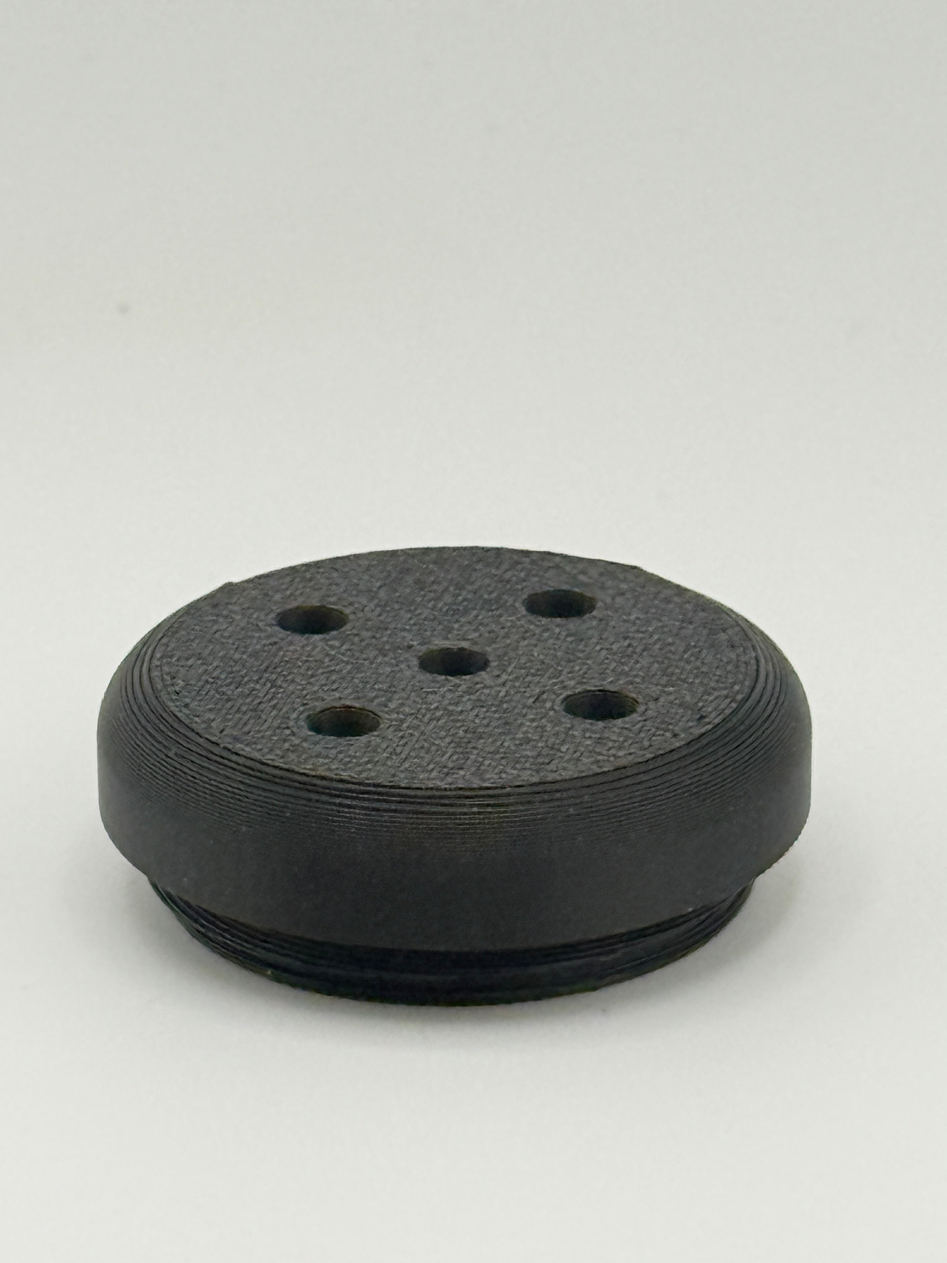Black perforated TrackMount tracker cap with five holes that let the tracker chime sound through
