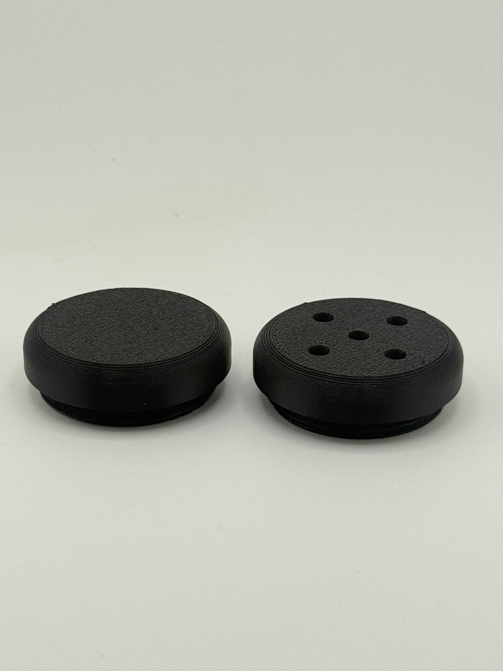 Two TrackMount tracker caps: a solid cap for weather protection and a perforated cap that lets the tracker chime through